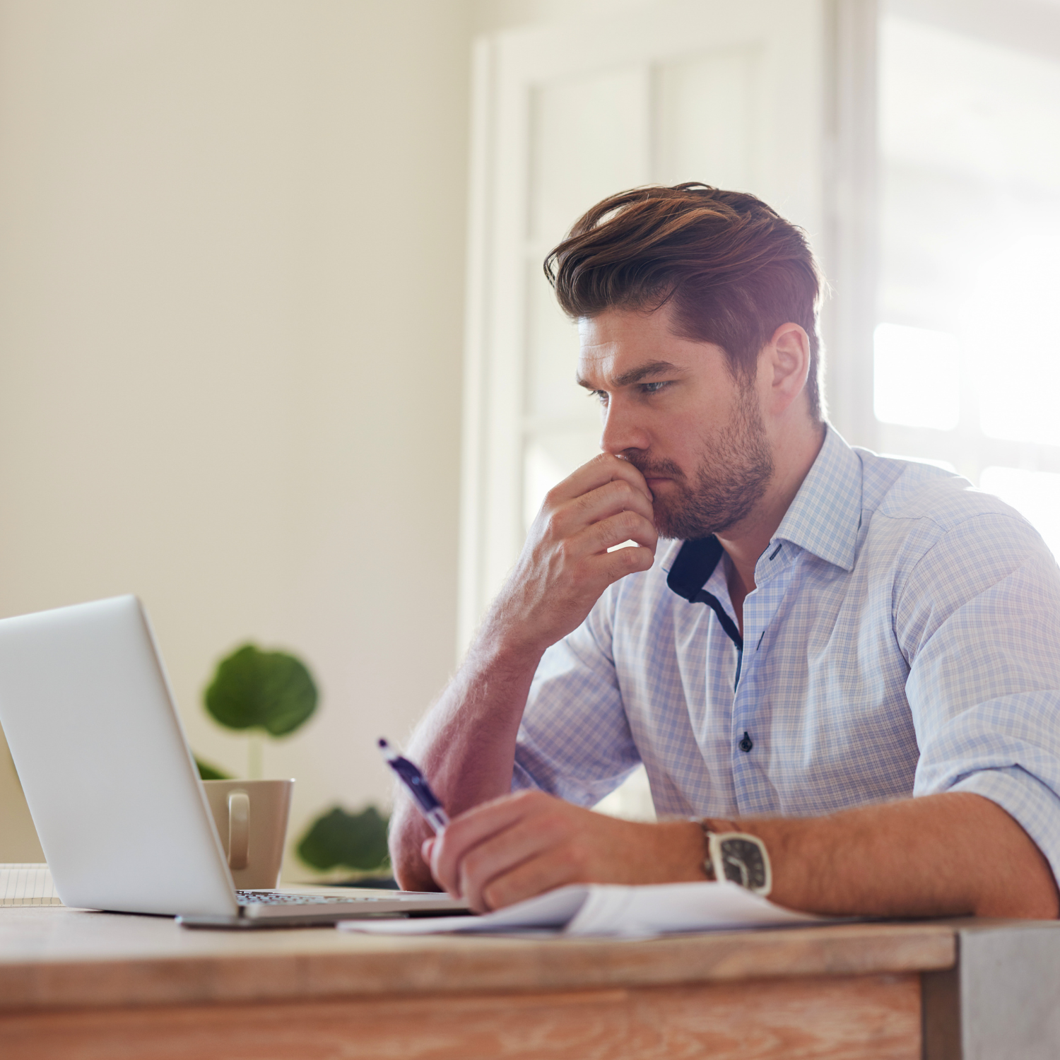 A man sits at a desk in front of a laptop