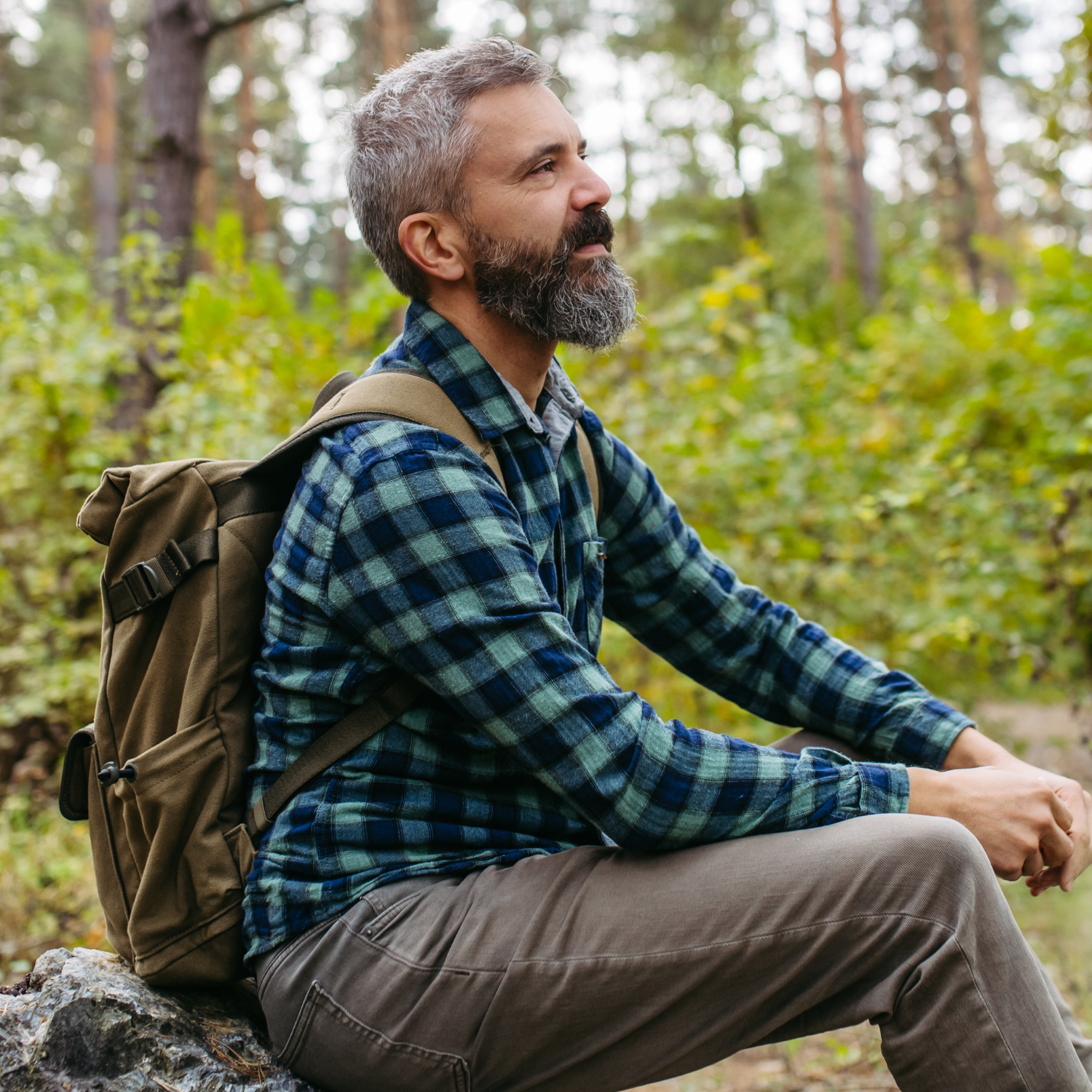 Man sitting outdoors in nature looking calm and relaxed, representing nervous system regulation and stress relief for better gut health.