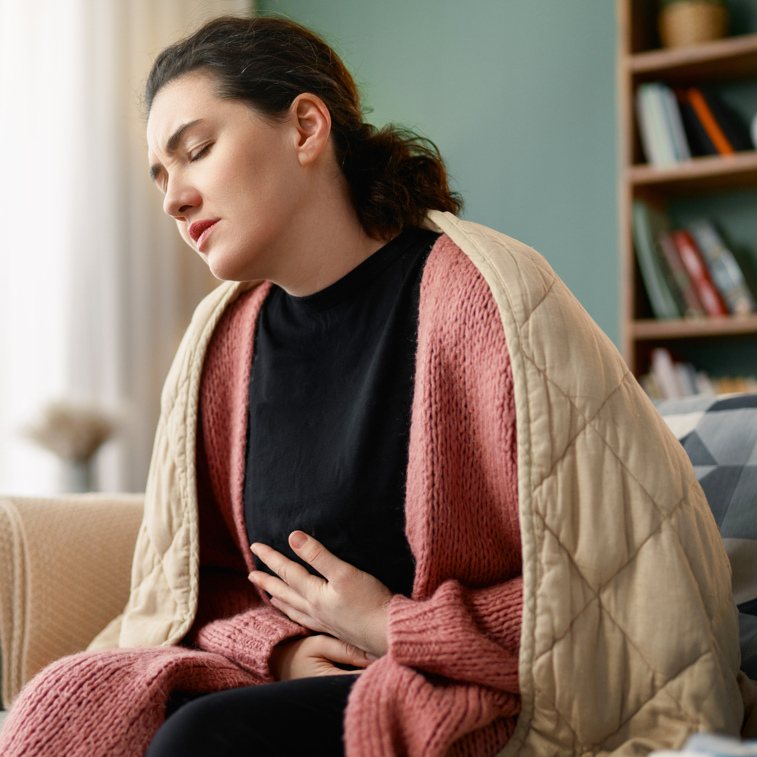 Woman holding stomach in discomfort, representing common signs of poor gut health such as bloating and digestive issues