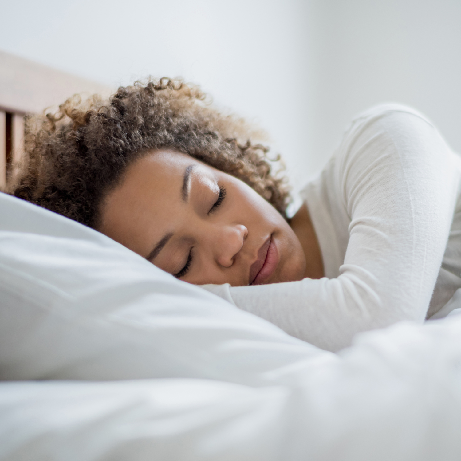 Person sleeping peacefully on a white pillow and bedding, illustrating restful sleep, relaxation, and healthy sleep habits.