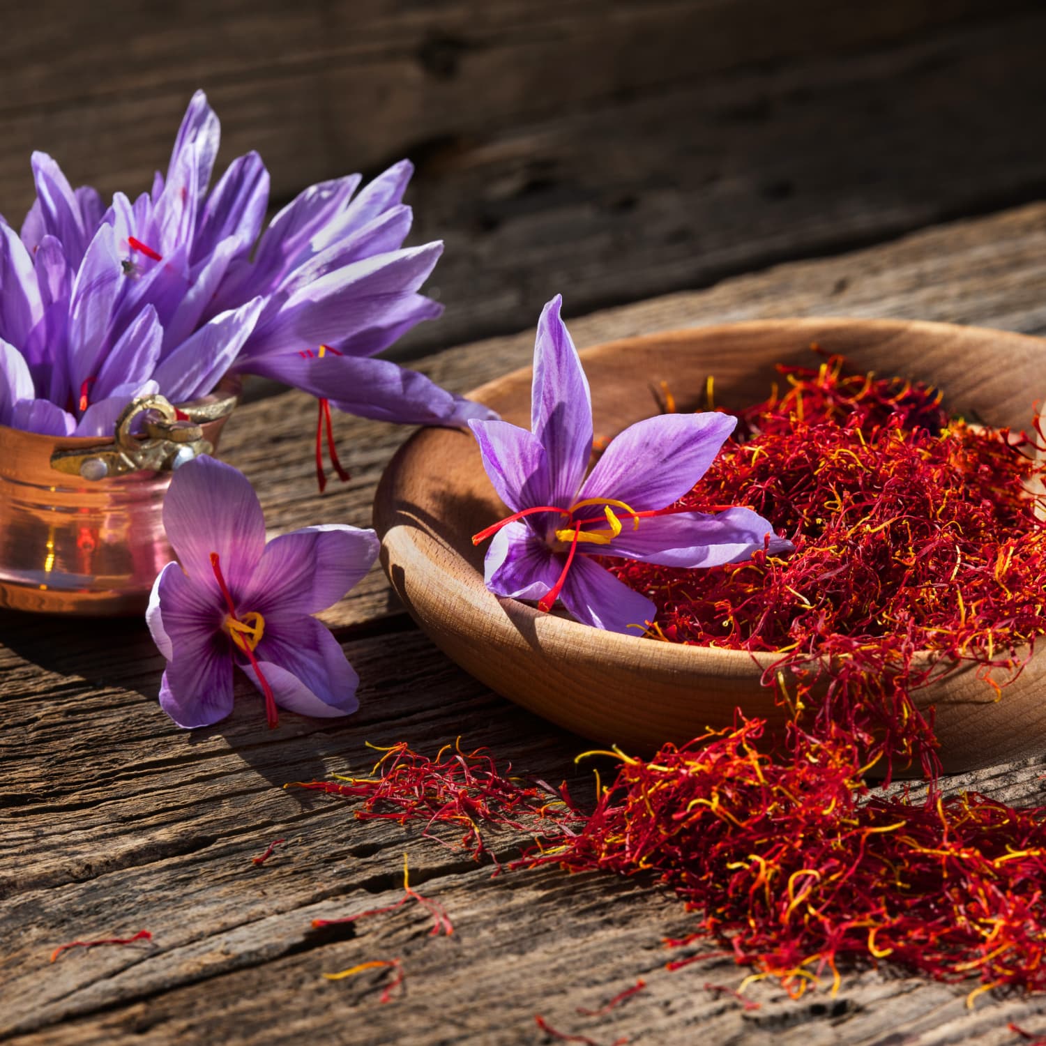 Purple crocus flower with vivid red saffron stigmas resting beside it.