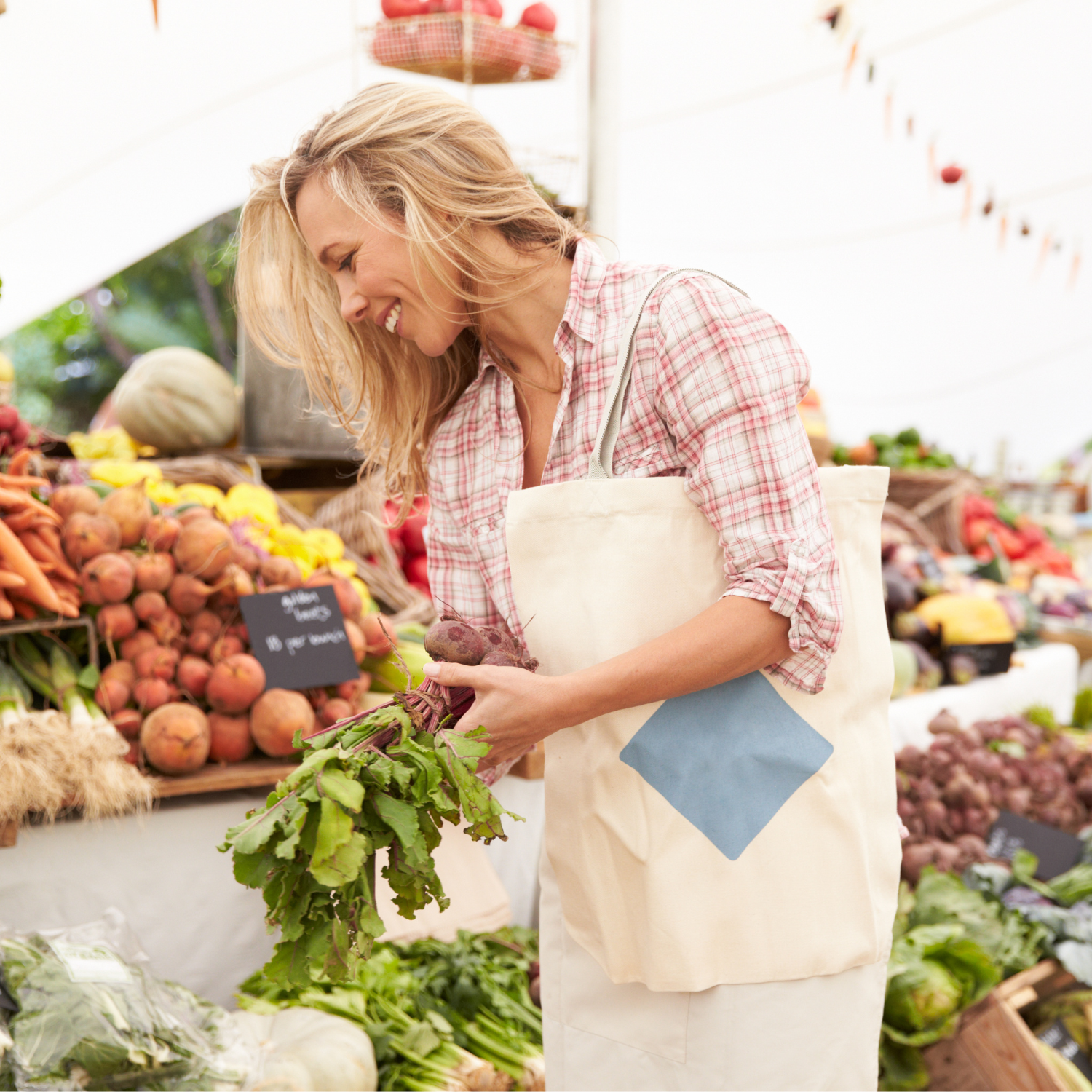 Woman shopping for fresh beets and vegetables at a local farmers market.